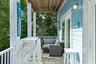 Covered porch featuring lap siding, white structural columns, wood-plank flooring, and double glass doors