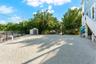 Gravel-surfaced exterior lot featuring a detached storage shed, perimeter chain-link fencing, and elevated home foundation