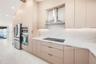 Custom flat-panel cabinetry, stone-surface countertops, full-height stone backsplash, stainless steel built-in double wall ovens, and stainless steel 