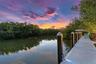Waterfront dock featuring composite decking, integrated LED lighting, and capped pilings set against a natural mangrove backdrop