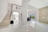 Open-concept interior featuring large-format tile flooring, a floor-to-ceiling textured stone accent wall, a staircase with custom metal railing, and 
