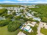 Aerial perspective of a waterfront property featuring direct canal access, private dockage, surrounding mangrove vegetation, and proximity to open bay