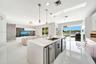 Kitchen featuring a waterfall-edge stone countertop, custom cabinetry, built-in dual wine refrigeration, recessed ceiling lighting, and large sliding 