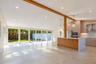Open-concept space featuring an exposed wood structural beam, floor-to-ceiling sliding glass doors, a large kitchen island with stone-finish waterfall