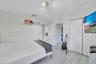 Neutral-toned wood-finish flooring, white paneled closet doors, adjustable multi-head track lighting, and built-in wall shelving