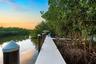 Private dock featuring composite decking, vertical pilings with conical caps, and mature mangrove surroundings along the water's edge