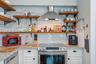 Kitchen area featuring white shaker-style cabinetry, natural stone countertops, white subway tile backsplash, stainless steel range with overhead vent