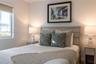 Neutral-toned walls, wood-finish paneling, horizontal window with roller shade, and light-toned built-in cabinetry