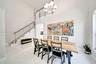 High-ceilinged room featuring large-format tile flooring, a multi-globe chandelier, and an open staircase with a metal cable railing system