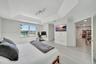 Tray ceiling with multi-directional track lighting, light-toned wood-finish flooring, and large window with water exposure