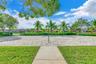 Sand volleyball court featuring a concrete walkway, perimeter landscaping, and mature palm trees