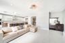 Open-concept space featuring polished tile flooring, two-tone cabinetry with an integrated breakfast bar, built-in stainless steel appliances, recesse