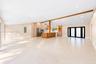 Expansive open-concept interior featuring vaulted ceilings, large-format tile flooring, a wood-accented center island, built-in cabinetry, and black-f