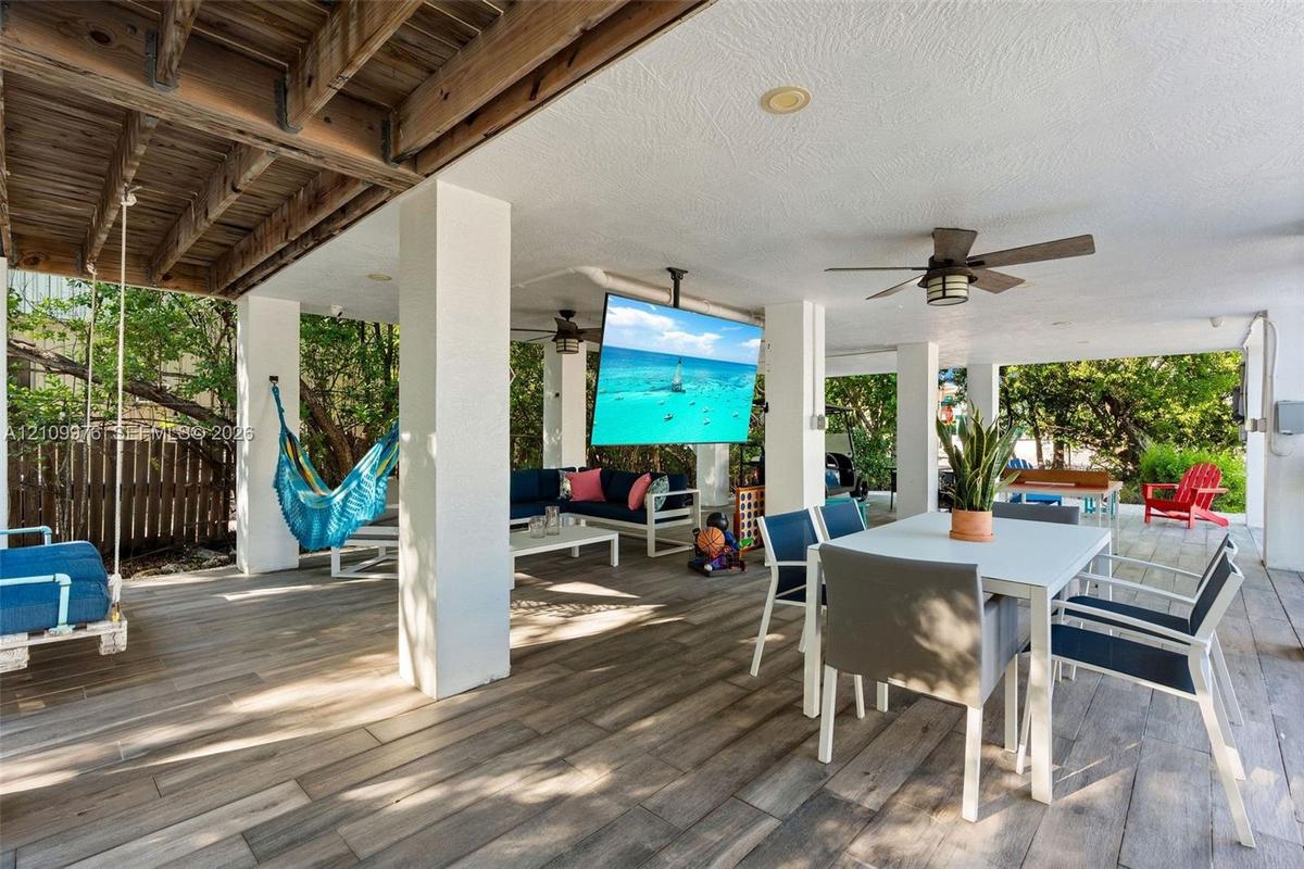 Covered patio featuring wood-finish flooring, recessed lighting, ceiling fans, and a ceiling-mounted television