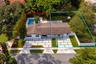 Aerial perspective of two properties featuring concrete paver driveways with grass inlay, rectangular in-ground pool, white vinyl fencing, and mature 