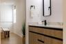 Floating vanity with wood-finish cabinetry, stone countertop, matte black faucet, and rectangular mirror with black frame