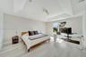 Tray ceiling, vertical panel accent wall, light-toned wood-finish flooring, and multi-pane window