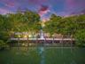 Waterfront wooden dock featuring structural pilings, integrated string lighting, and direct access to mature mangrove vegetation