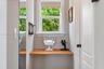 Built-in wooden wall-mounted desk, dual-pane window with white trim, and interior panel door with black hardware