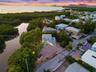 Aerial perspective of a multi-story residence featuring a metal roof, elevated structural design, expansive gravel grounds, and direct positioning alo