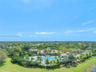 Aerial view of a sprawling estate featuring a large swimming pool, expansive manicured lawn, established palm trees, and professional landscaping