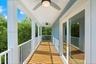 Covered balcony featuring wood-plank flooring, white metal railing, dual ceiling fans with integrated lighting, and horizontal lap siding