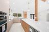Kitchen featuring flat-panel cabinetry, a spacious stone-surfaced island, integrated stainless steel appliances, a structural wood pillar, and recesse