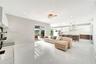 Open-concept living space featuring high-gloss tile flooring, recessed lighting, a modern chandelier, and a kitchen equipped with two-tone cabinetry a
