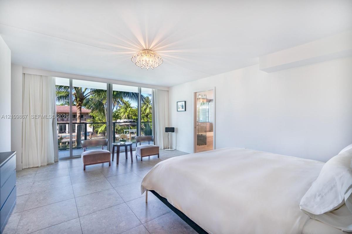Full-height sliding glass doors with black metal framing, large-format tile flooring, recessed ceiling fixture, and glass-paneled interior door