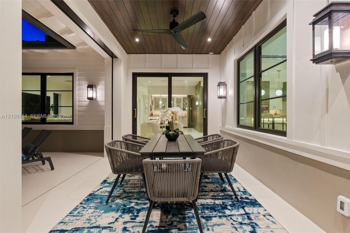 Covered patio featuring a wood-plank ceiling, matte black ceiling fan, recessed lighting, wall-mounted exterior lanterns, and multi-panel sliding glas