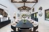 Vaulted ceilings with exposed wood beams, polished stone flooring, custom built-in cabinetry, floor-to-ceiling sliding glass doors, and a decorative t