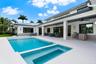 Modern exterior featuring board-and-batten siding, a covered patio with integrated ceiling fans, a built-in outdoor kitchen, and a swimming pool with 