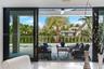 Large-format sliding glass doors, covered concrete patio, built-in ceiling fan, swimming pool, and privacy fencing