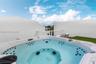 Rooftop terrace featuring a built-in spa, glass panel railing, and synthetic turf surfacing