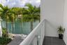 Covered balcony featuring glass railing, tiled flooring, and waterfront access with a paved walkway