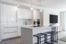 Modern kitchen featuring high-gloss cabinetry, a central island with a solid-surface countertop, integrated appliances, and pendant lighting