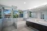 Bathroom featuring a floating dual vanity with rectangular vessel sinks, a glass-enclosed shower, a deep soaking tub, and floor-to-ceiling windows