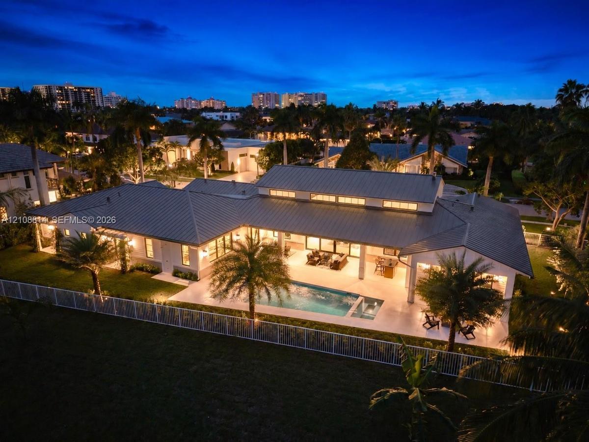 Single-story residence featuring a metal roof, clerestory windows, an expansive covered patio, a rectangular swimming pool, and a fenced perimeter