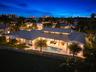 Single-story residence featuring a metal roof, clerestory windows, an expansive covered patio, a rectangular swimming pool, and a fenced perimeter