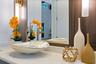 Vanity featuring a stone-surface countertop, vessel sink, metallic-finish faucet, framed mirror, and vertical wall-mounted lighting