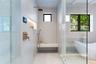 Walk-in shower featuring a built-in stone bench, rain showerhead with handheld sprayer, recessed shelving with integrated lighting, digital control in