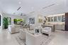 Open-concept living space featuring high ceilings with recessed lighting, large-format tile flooring, a dedicated wet bar with glass-front cabinetry, 