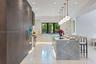 Kitchen featuring floor-to-ceiling cabinetry, a waterfall-edge stone island, recessed ceiling lighting, a row of spherical pendant lights, and large-f