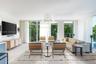 Floor-to-ceiling glass windows, stone-finish flooring, contemporary geometric chandelier, and recessed wall lighting