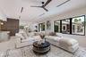 Open-concept living space featuring high ceilings with recessed lighting, a modern ceiling fan, expansive black-framed windows, and light-toned floori