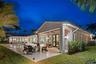 Covered rear terrace featuring a concrete patio, integrated ceiling fan, and wall-mounted exterior lighting, complemented by a swimming pool and board
