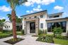 Modern exterior featuring white vertical siding, a stone veneer entryway surround, metal roof accents, expansive dark-framed windows, and a paved walk