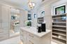 Custom built-in cabinetry with integrated lighting, central island with stone countertop, full-length mirror, glass-front display shelving, and orb-st