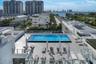 Rooftop terrace featuring a rectangular swimming pool, expansive stone-tile decking, and glass panel railing