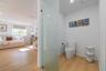 Wood-finish flooring, frosted glass enclosure, and modern one-piece toilet